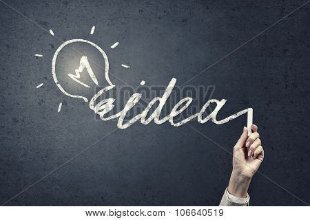 Human hand darwing light bulb as idea concept with chalk