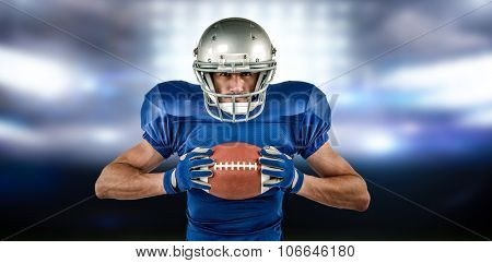 Portrait of confident sports player holding ball against sports pitch