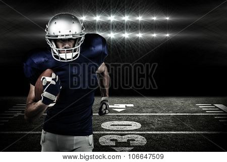 Confident American football player running with ball against spotlights