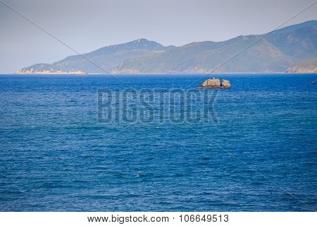 Fishing Boat Amidst Azure Sea Against Hilly Tropical Island