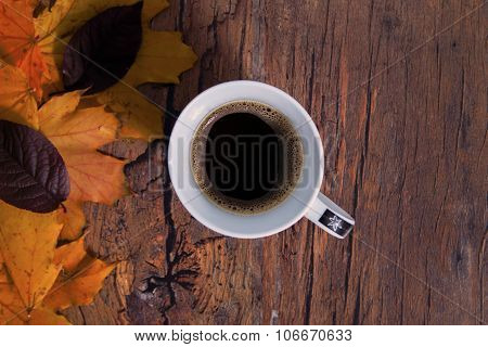 Cup of coffee on the desk among yellow leafs