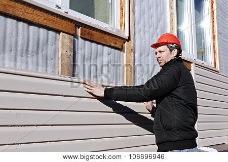 A Worker Installs Panels Beige Siding On The Facade