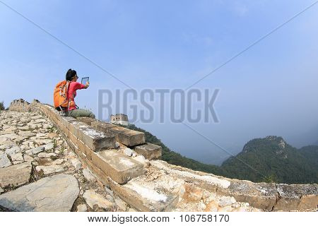 young woman hiker use digital tablet sit on chinese great wall