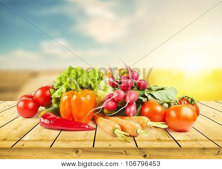 fruits and vegeetables on wooden desk and autumn field on background