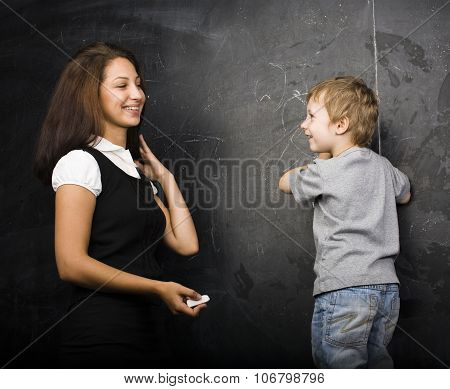 little cute boy in glasses with young real teacher, classroom studying at blackboard school kido clo