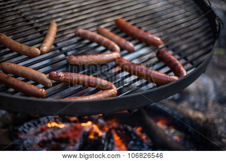 Cooking sausages on the outdoor stove with fire close up
