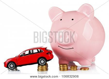 Piggy bank with car toy and coins around, isolated on white