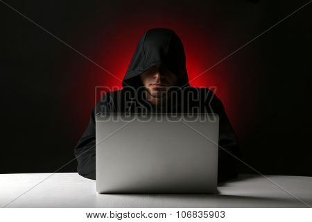 Hacker with computer and laptop on colorful dark background 
