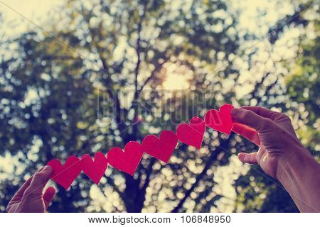 Two Hands Holding Paper Cut-out Hearts