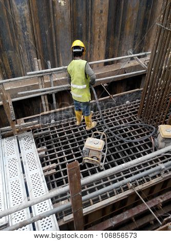 Construction Workers Using Concrete Vibrator to compact the concrete slurry