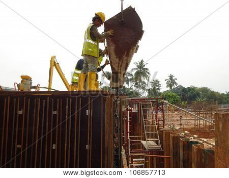 Construction workers pouring concrete slurry into reinforcement concrete wall formwork