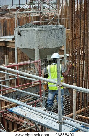 A group of construction workers pouring concrete slurry into pile cap formwork