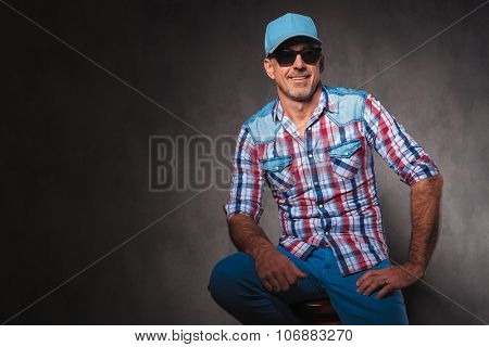 confident old casual man with baseball hat and sunglassed sitting and looks away from hte camera