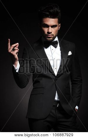 Picture of a young elegant business man snapping his fingers while looking at the camera.