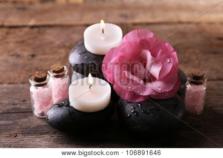 Alight candles, pebbles and fresh aroma flower composition on wooden background