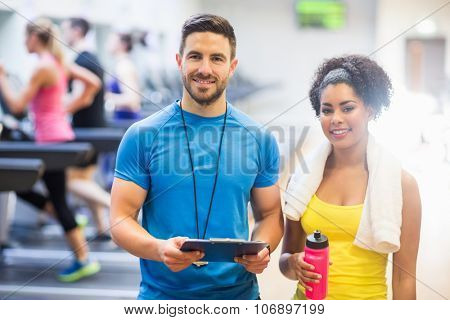 Trainer and client smiling at camera at the gym