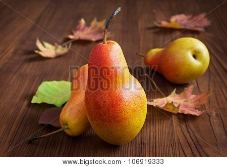 Ripe pear and autamn leaves on a wooden table. Harvest concept.