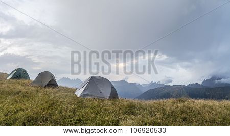 panorama of the mountains, in a clearing, there are three tents