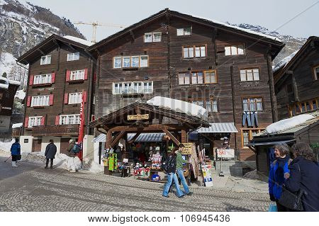 Tourists walk by the street in Zermatt, Switzerland. Wooden Houses Of Zermatt.