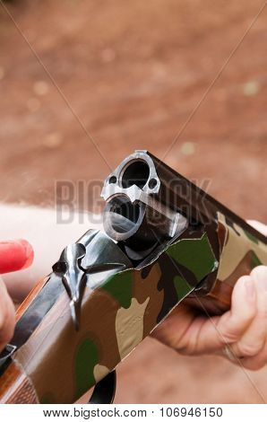 Smoking gun concept,  a double barreled over/under shotgun immediately after firing with shallow depth of field focused on the smoke leaving the breech