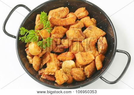 pork greaves with parsley in black skillet