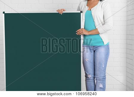 Woman in causal with green blackboard against brick wall, close up