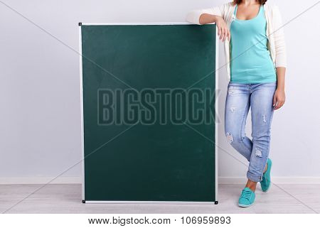 Woman in causal with green blackboard on grey background, close up