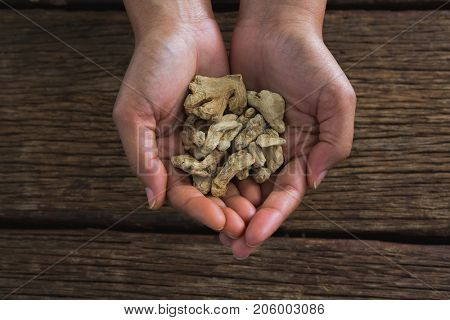 Close-up of handsholding dried ginger against wooden table