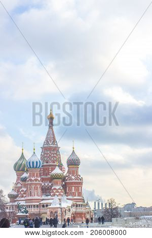 View of Russia's symbolic center its Saint Basil Cathedral masterpiece of Russian architecture with elegant onion shaped domes with pyramidal roofs and Crowd travelers under Clear sky and blue shades background in Red square at Moscow, Landscape of colorf