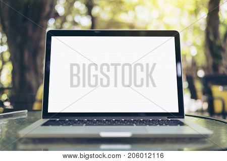 Mockup image of laptop with blank white screen on glass table at outdoor with green nature background