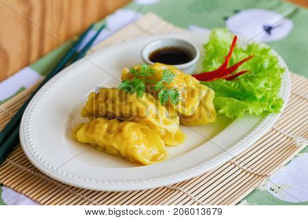Homemade minced pork dumpling on white plate served with dipping soy sauce on wood table. Delicious dumpling or dim sum for breakfast or lunch or dinner. Dim sum or dumpling is popular Chinese food. Dumplings or Dim sum ready to served.