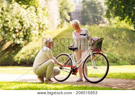active old age, people and lifestyle concept - happy senior couple with fixie bicycle at summer city park