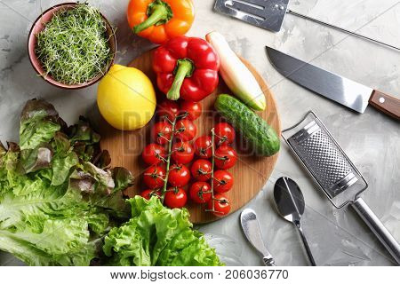 Wooden board with vegetables and utensils on kitchen table. Cooking classes concept