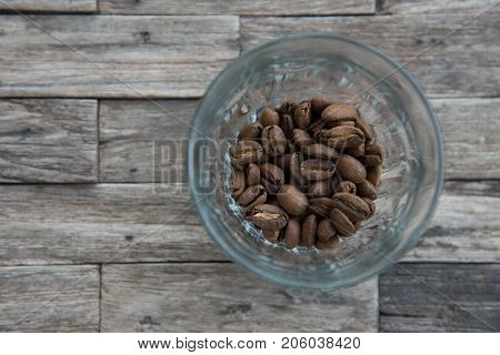 roasted coffee beans in a crystal glass on a wooden coffee table background