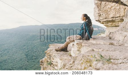 Traveler young woman resting on cliff Eagle shelf in summer Mezmay Krasnodar region Russia.