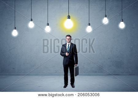 Handsome businessman in an empty space with bulbs above and uninspired face