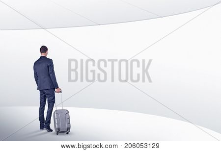 Businessman with back walking in a white waiting room with empty walls around