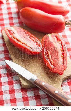 Halved San marzano tomatoes on cutting board.