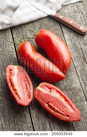 Halved San marzano tomatoes on old wooden table.