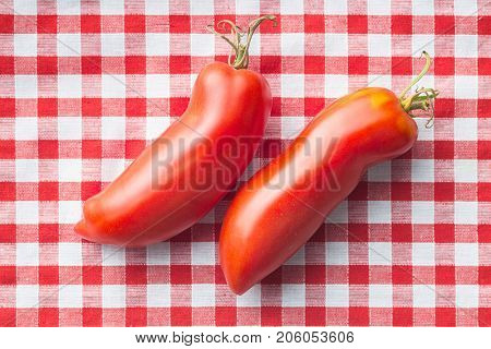 San marzano tomatoes on checkered tablecloth.
