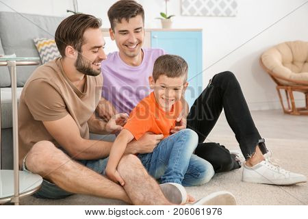 Homosexual male couple with foster son at home. Adoption concept