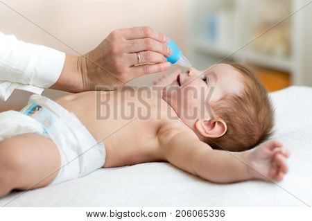 doctor hand cleans baby's nose with vacuum cleaner