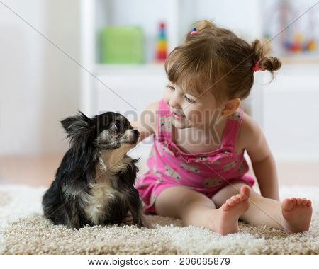 Cute baby girl looking at dog. Closeup portrait.