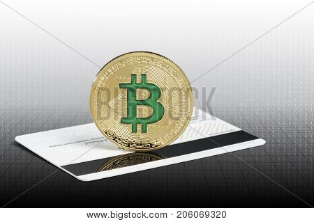 Cryptocurrency physical green bitcoin coin over the credit card.