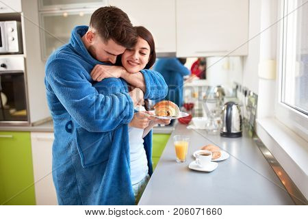 Young happy couple hugging in kitchen in the morning