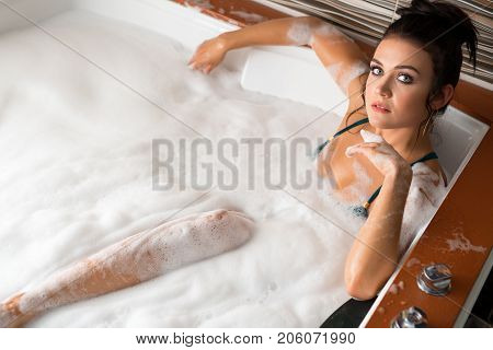 Pretty sexy brunette in green bicini enjoying jacuzzi in sauna top view