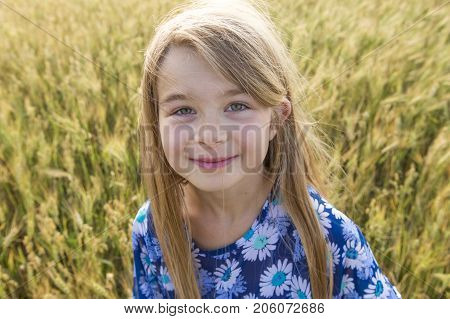 An Adorable little girl playing in the wheat field on a warm summer day