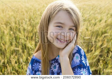 An Adorable little girl playing in the wheat field on a warm summer day