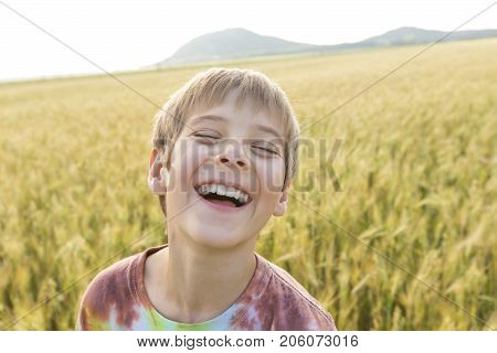 An Adorable little boy playing in the wheat field on a warm summer day