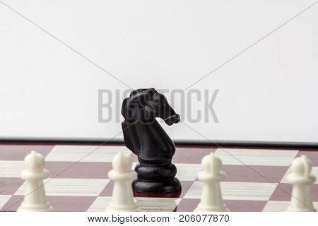 chess black horse in front of white pawns. concept of struggle. Isolated on white background.